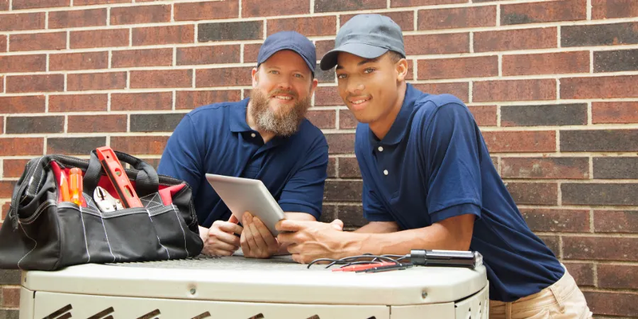 hvac technicians posing for pic over an air conditioner